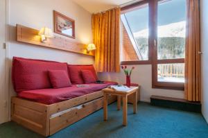 a living room with a red couch and a window at Résidence Pierre & Vacances Le Peillon in Méribel