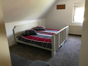 a bedroom with a white bed with a striped blanket at Haus Irmgard in Schlierschied