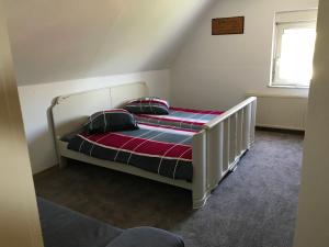 ein Schlafzimmer mit einem weißen Bett und einer gestreiften Decke in der Unterkunft Haus Irmgard in Schlierschied