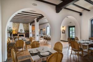 un restaurante con paredes blancas, mesas y sillas en Hotel Doña Lola Zahara en Zahara de los Atunes