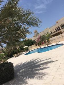 a swimming pool with chairs and a palm tree at Townhouse Ras al Khaimah in Ras al Khaimah