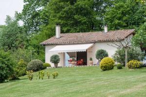 una pequeña casa blanca con un patio de césped en Gite Au Bouzigues, en Monlaur-Bernet