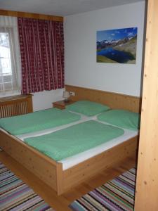 - une chambre avec un lit en bois et des oreillers verts dans l'établissement Apartment Fernerblick, à Neustift im Stubaital