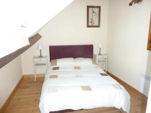 a bedroom with a white bed and two night stands at Lavender Cottage in Chézelles