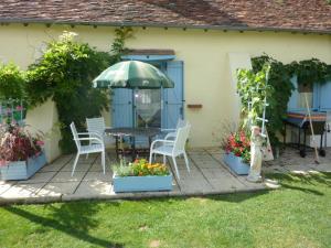 um pátio com uma mesa, cadeiras e um guarda-sol em Lavender Cottage em Chézelles