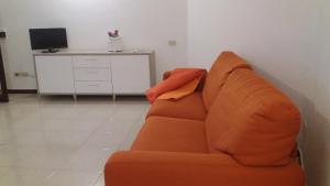 サンタ・テレーザ・ガッルーラにあるAppartamento Fronte Mareのリビングルーム(オレンジ色のソファ、テレビ付)