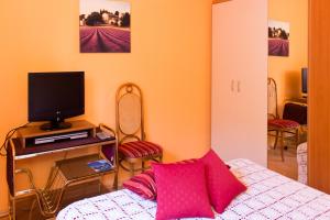 a room with a bed and a television and chairs at Apartmani Danja in Kaštela