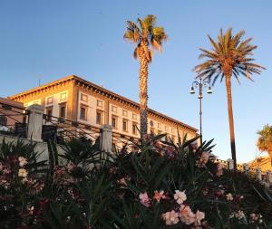 a building with palm trees and flowers in front of it at Casa Terme in Sciacca