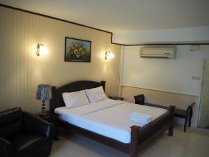 a hotel room with a bed and a chair at The Hotel Nakhonsawan in Nakhon Sawan