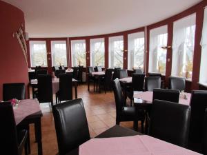 a dining room with tables and chairs and windows at Hotel Seeblick in Saalburg