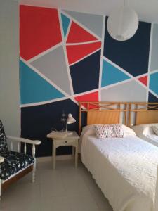 1 dormitorio con una pared colorida, 1 cama y 1 silla en Isla Canela Natura, en Isla Canela
