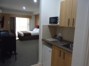 Habitación de hotel con 1 dormitorio con 1 cama y cocina en Albury Regent Motel en Albury