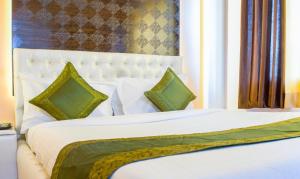 a bedroom with a white bed with green pillows at Treebo Trend Naunidh Suites in Pune