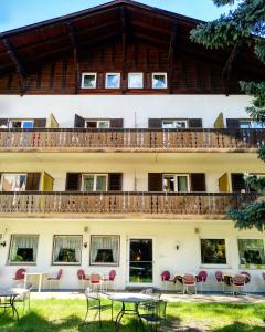 un bâtiment avec des tables et des chaises devant lui dans l'établissement Hotel Pension Schweitzer, à Silandro