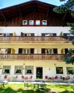 a building with tables and chairs in front of it at Hotel Pension Schweitzer in Silandro