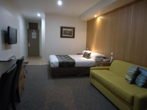 a hotel room with a couch, chair and a television at Albury Regent Motel in Albury