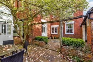 a brick house with a table and chairs in front of it at The Hollies in South Kilworth