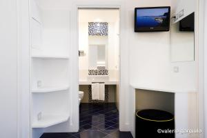 a bathroom with a toilet and a tv on a wall at Hotel Nice in Sorrento