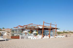 a restaurant on the beach with chairs and umbrellas at Hipotels Barrosa Park in Chiclana de la Frontera