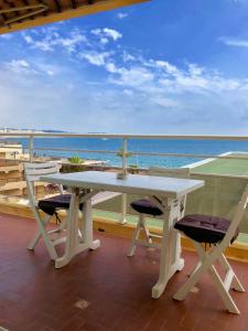 einen weißen Tisch und Stühle auf einem Balkon mit Meerblick in der Unterkunft Le Fourneau beach in Fréjus