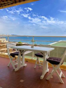 een witte tafel en stoelen op een balkon met uitzicht op de oceaan bij Le Fourneau beach in Fréjus