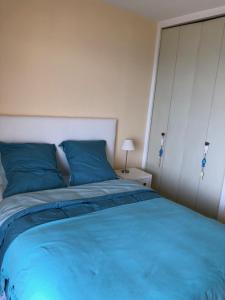 een slaapkamer met een groot bed met blauwe kussens bij Le Fourneau beach in Fréjus