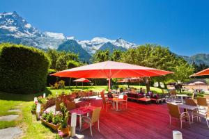 a restaurant with tables and chairs with mountains in the background at Aiguille du Midi - H&ocirc;tel & Restaurant in Chamonix-Mont-Blanc