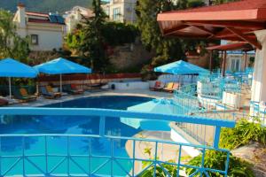 a swimming pool with chairs and blue umbrellas at Soothe Hotel in Kalkan