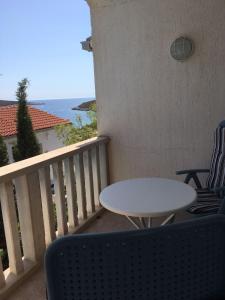 una mesa blanca y sillas en un balcón con vistas al océano en Kuća Roza, en Rukavac