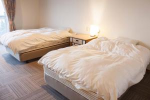 two twin beds in a room with a nightstand and two beds sidx sidx sidx at Irou in Tonosho