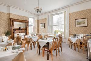 un restaurante con mesas y sillas blancas y una ventana en Acorn House, en Keswick