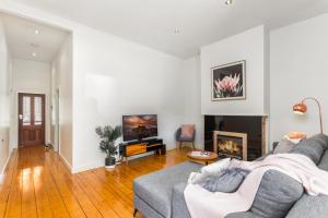 a living room with a gray couch and a fireplace at Central Bendigo Cottage, walk to everywhere!! in Bendigo