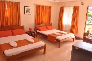 two beds in a room with orange curtains at SLAM'S Garden Dive Resort in Malapascua Island