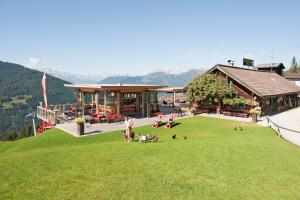 een groep mensen en honden op het gras voor een gebouw bij Reitlehenalm in Altenmarkt im Pongau