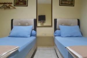 two beds in a room with blue pillows at Pondok Seruni Kemanggisan Jakarta in Jakarta