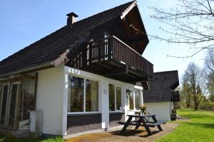 una piccola casa bianca con balcone e tavolo da picnic di Knusperhäuschen Edersee a Frankenau