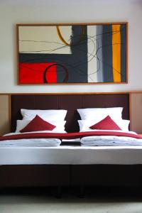 a bed with red pillows and a painting above it at Landhotel-Neunburg in Neunburg vorm Wald