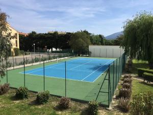 una pista de tenis con una red en un patio en Studio Hameau au soleil, en Plage dʼArgelès