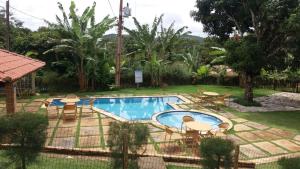 a pool with tables and chairs next to a house at Guaramiranga Monte Verde in Guaramiranga