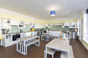 a large kitchen with tables and white cabinets at YHA Swanage in Swanage