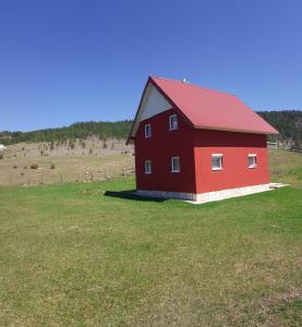 a red barn with a red roof in a field at Apartmani Bozovic in Žabljak
