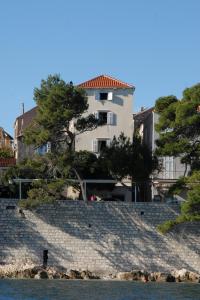 ein weißes Gebäude auf einem Hügel mit Bäumen davor in der Unterkunft Apartments Tedeschi in Korčula