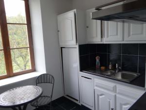 a kitchen with white cabinets and a table and a sink at Domaine de La Bessade in Le Bugue