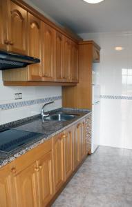 a kitchen with wooden cabinets and a sink at Apartamentos Imperial in Salou