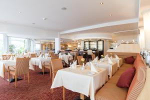 a dining room with white tables and chairs at Hotel Strandidyll in Grömitz