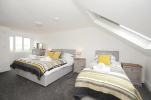 2 bedden in een kamer met witte en gele kussens bij York Boutique House- spacious & stylish with free parking in York