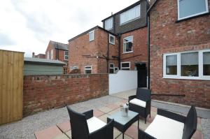 een patio met stoelen en tafels en een bakstenen muur bij York Boutique House- spacious & stylish with free parking in York