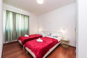 1 dormitorio con 2 camas con sábanas rojas y ventana en Apartman Micko en Privlaka