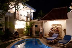 a group of people standing next to a house at night at Mango 5 Hotel in Amed