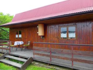 een houten hut met een tafel en stoelen op een terras bij Tanie Spanie in Wysowa-Zdrój